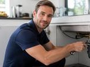 Plumber repairing pipes under a kitchen sink